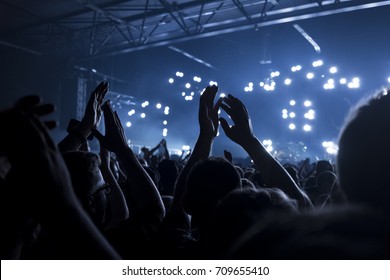 Concert goers applauding inside a music venue - selective focus