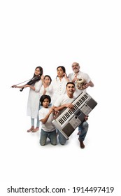Concert of Indian family of six playing music instruments in a group and senior lady singing, standing against white background