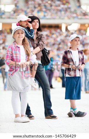 Concert at the stadium. Spectators are on the pitch. Family with three children close up