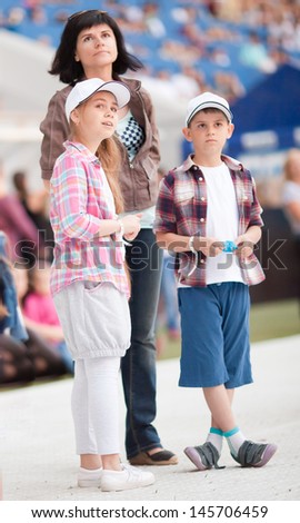 Concert at the stadium. Spectators are on the pitch. Family with two children close up