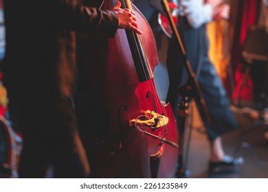 Concert view of a contrabass violoncello player with vocalist and musical band during jazz orchestra band performing music, violoncellist cello jazz player on stage
					