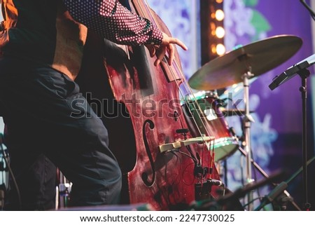 Concert view of contrabass violoncello player with musical band during jazz orchestra band performing music, violoncellist contrabassist cello jazz player on stage

