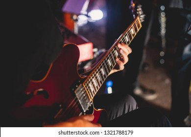 Concert view of an electric guitar player with vocalist and musical band in the background - Powered by Shutterstock
