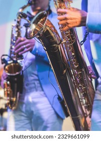 Concert view of saxophonist in a blue and white suit, a saxophone sax player with vocalist and musical band during jazz orchestra show performing music on stage in the scene lights - Shutterstock ID 2329661099