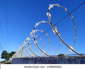 The concertina fence installed on a wall in a day with gorgeous blue sky and clouds