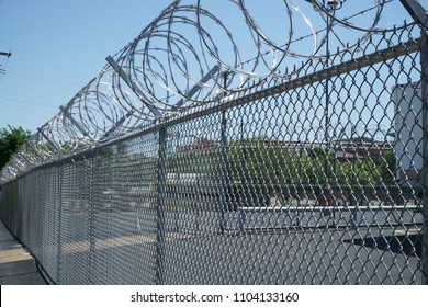 Concertina razor wire is pictured running the length of a chain link fence.