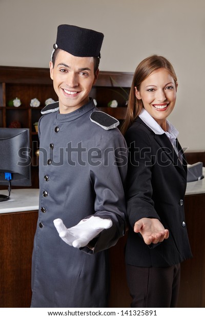 Concierge and receptionist in hotel offering\
welcome to guests