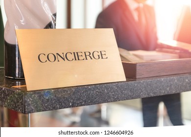 Concierge Service Desk Counter With Happy Employee Staff Receptionist Working In Front Of Hotel With Tourist Guest Business Customer.