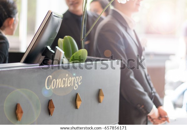Concierge service desk counter\
with staff team working in front of hotel with tourist business\
customer.