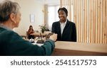 Concierge, women and hotel reception with payment, credit card and customer service. Spa lobby, smile and transaction with business support, guest help and booking agent at resort counter with tech