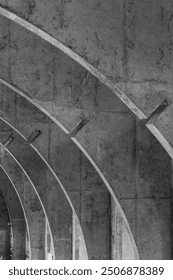 Concrete arches create an abstract pattern, with a weathered texture and intersecting lines casting subtle shadows in grayscale.