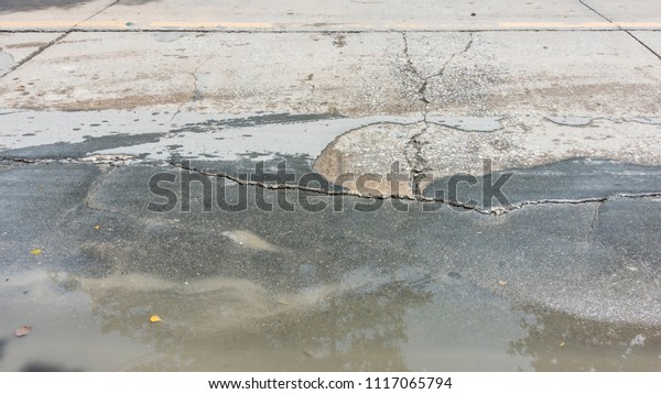 Concrete asphalt cracks on the road, Line rough\
surface and grey cracked asphalt road, Puddle Water on the Crack\
road, flooded and road