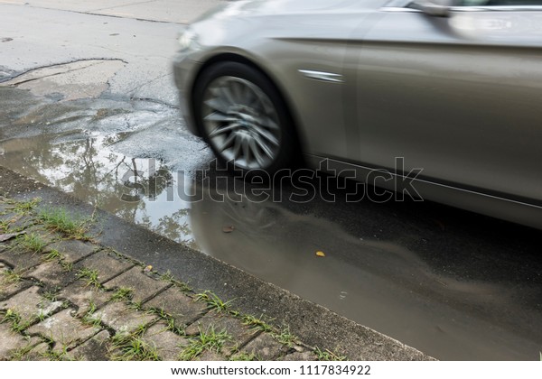 Concrete asphalt cracks on the Road, Line rough\
surface and grey cracked asphalt road, Wheels ran over the water,\
Car driving on a flooded\
road