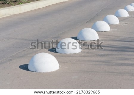 Concrete ball spheres lie down on the road. Bollards. Urban. Pavement. Control. Drive. Grey. Path. Planet. Public. Security. Traffic. Nobody. Object. Row. Stop. Problem. Solution