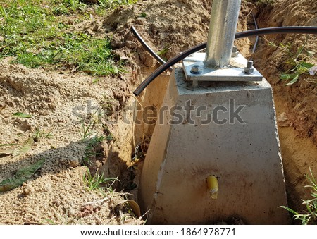 The concrete bar that forms the base for the light pole has a large bolt to hold the light pole. Placed in underground holes