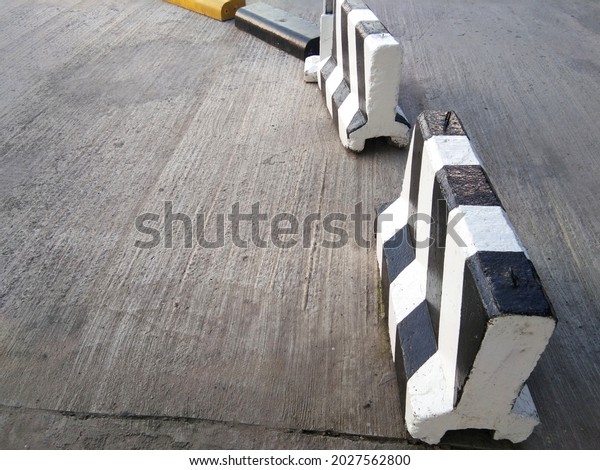 Concrete BARRIER\
black with white trim Place a barrier in the middle of the road to\
divide lanes with\
buildings.