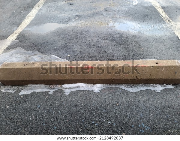 A concrete beam at the edge of a parking spot.\
The cement beam is at the base of the parking space so that cars\
don\'t drive too far forward.