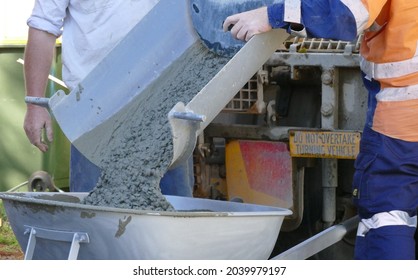Concrete being poured into a wheelbarrow from a mixer truck
