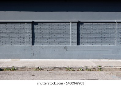 Concrete And  Brick Wall Painted Gray,  With A Sidewalk And An Asphalt Road In Front. Background For Copy Space