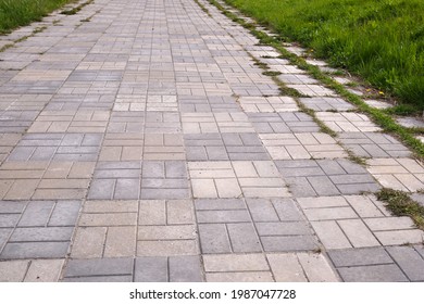 Concrete bricks footpath on the green grass in the park, abstract background of tiles, footpath, sidewalk, 
