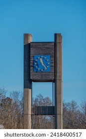 Concrete clock-tower with a blue watchface during autumn fall