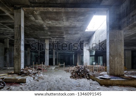 Concrete construction of basement of large building. Panorama inside the modern construction site in dark. Contemporary structure under construction with concrete walls, pillars, ceiling and floor.