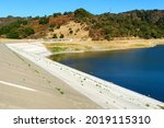 Concrete dam of almost dried, low water level Stevens Creek reservoir in San Francisco Bay Area, California.