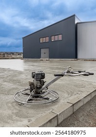 Concrete finishing process using a power trowel machine on a freshly poured concrete slab at industrial building construction site
