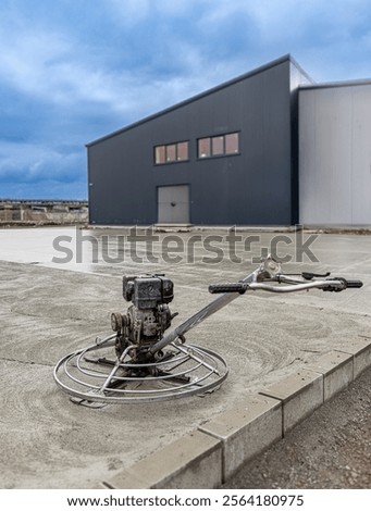 Concrete finishing process using a power trowel machine on a freshly poured concrete slab at industrial building construction site