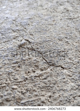  A concrete floor showing signs of cracking, forming patterns that convey a sense of aging and wear. The floor is composed of a mixture of cement and sand, a common combination for construction