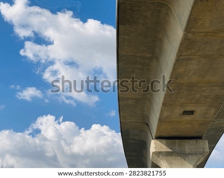 Concrete flyover bridge structure under blue sky with fluffy clouds