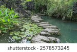 A concrete footpath made of fancy sections winds through the pond. The leaves of water lilies on the water. Lush green vegetation on the shore of the reservoir.China.Heavenly Star Bridge Tianxing Qiao