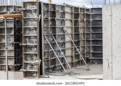 Concrete formwork structures are set up at a construction site, showcasing the assembly of molds for pouring concrete. Steel reinforcements and scaffolding provide support as workers prepare