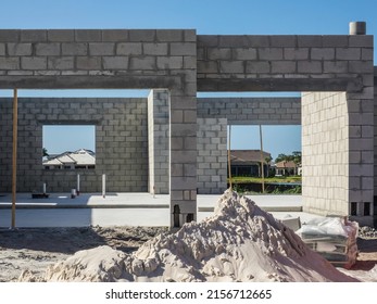 Concrete foundation and shell of a single-family house under construction, with a pile of sand for mortar mix in foreground, in a suburban development on a sunny morning in southwest Florida - Shutterstock ID 2156712665