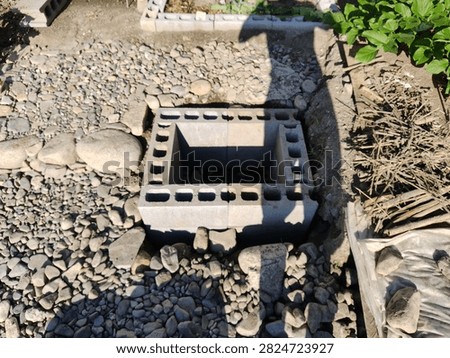 Concrete hollow blocks structure built into gravel and stone ground in a garden.