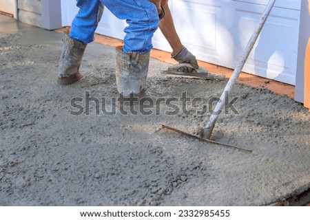 Concrete leveling workers on construction site with mix trowel leveling to concrete driveway