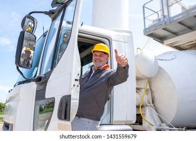 Concrete mixer truck driver with thumb up enters the cabin of his truck