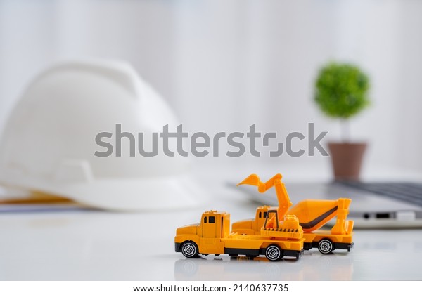 Concrete mixer truck and excavator on\
architect\'s desk, Engineering objects, Construction\
site.