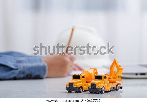 Concrete mixer truck and excavator on\
architect\'s desk, Engineering objects, Construction site.\
