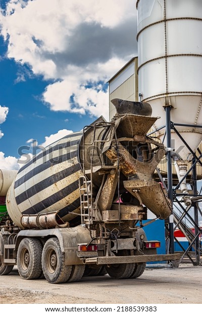 Concrete mixer truck in front of a\
concrete batching plant, cement factory. Loading concrete mixer\
truck. Close-up. Delivery of concrete to the construction\
site.
