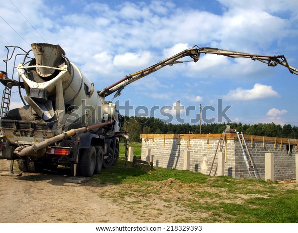 concrete mixer truck with pump\
on the site is preparing to pour concrete on the roof of a small\
house