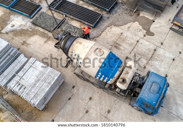 A concrete mixer truck transports concrete\
through a construction site. Transposing liquid concrete with\
special vehicles.