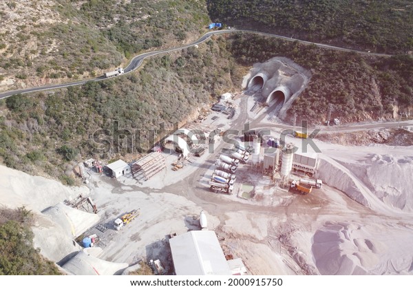 Concrete mixer trucks, concrete\
batching plant and construction materials at motorway tunnel\
construction site aerial view. State road D400, Mersin province,\
Turkey
