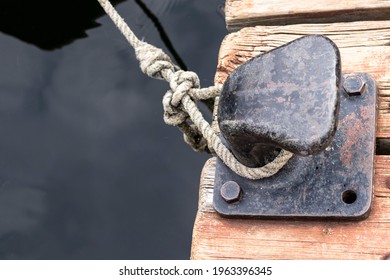 Concrete mooring bollard with a rope around it on a pier.