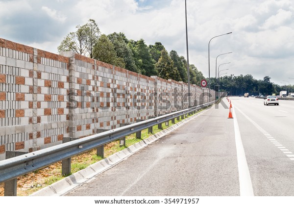 Concrete noise barrier wall along busy\
noisy highway insulate surrounding residential\
area