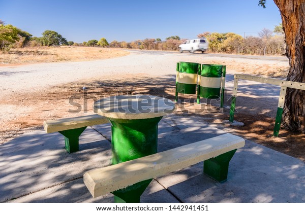 Concrete\
picnic table and benches placed beside a tree for shade, typically\
placed every 10-20kms along roads in\
Namibia