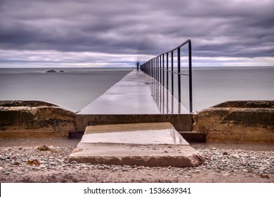 Concrete pier leading a ghost shadow to eternity in overcast stormy weather.