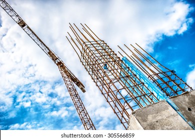 Concrete pillars on industrial construction site. Building of skyscraper with crane, tools and reinforced steel bars