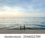 concrete platform on calm sea background. concrete beach with metal handrails. nature pool. horizon. waterline background. seawater surface. minimalistic background