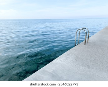 concrete platform on calm sea background. concrete beach with metal handrails. nature pool. horizon. waterline background. seawater surface. minimalistic background - Powered by Shutterstock